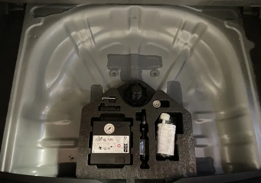 Compartiment de roue de secours vide avec kit de réparation et compresseur dans un CUPRA Formentor gris mat.