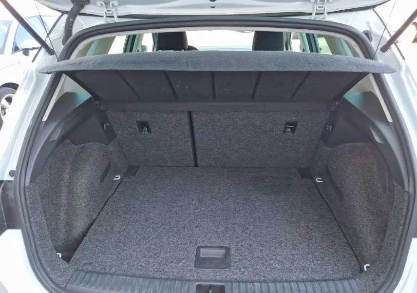 Coffre ouvert vu de l’arrière d’un SEAT Arona blanc alpin métal avec toit noir, montrant l’espace de chargement vide et la tablette arrière relevée.