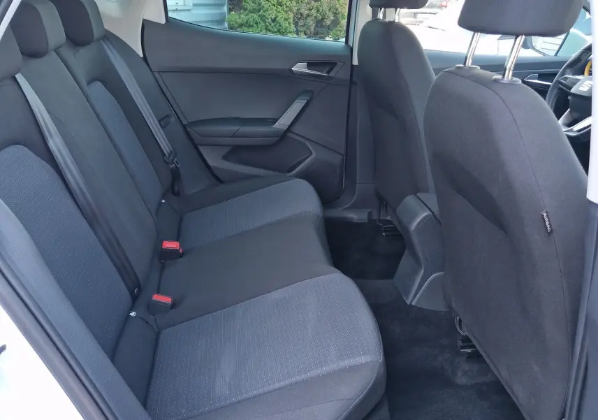 Vue intérieure arrière côté gauche d'une SEAT Arona 2025, sièges tissu noir avec ceinture de sécurité grise.