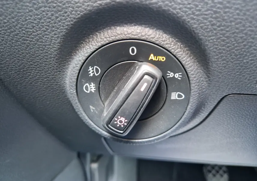 Gros plan sur le sélecteur de phares noir dans l’habitacle du SEAT Arona 2025, avec options d’éclairage automatique.