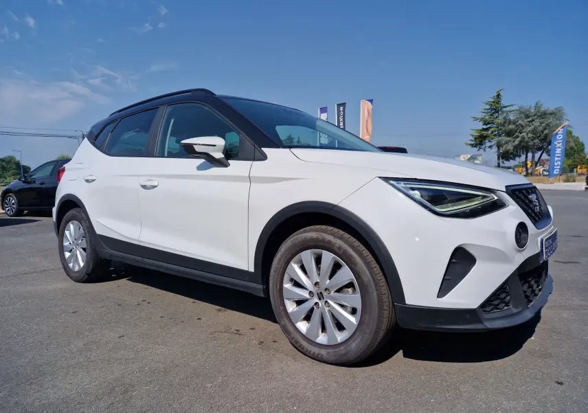 SEAT Arona blanc alpin métal avec toit noir, vue 3/4 avant droit, sur parking extérieur par temps clair.