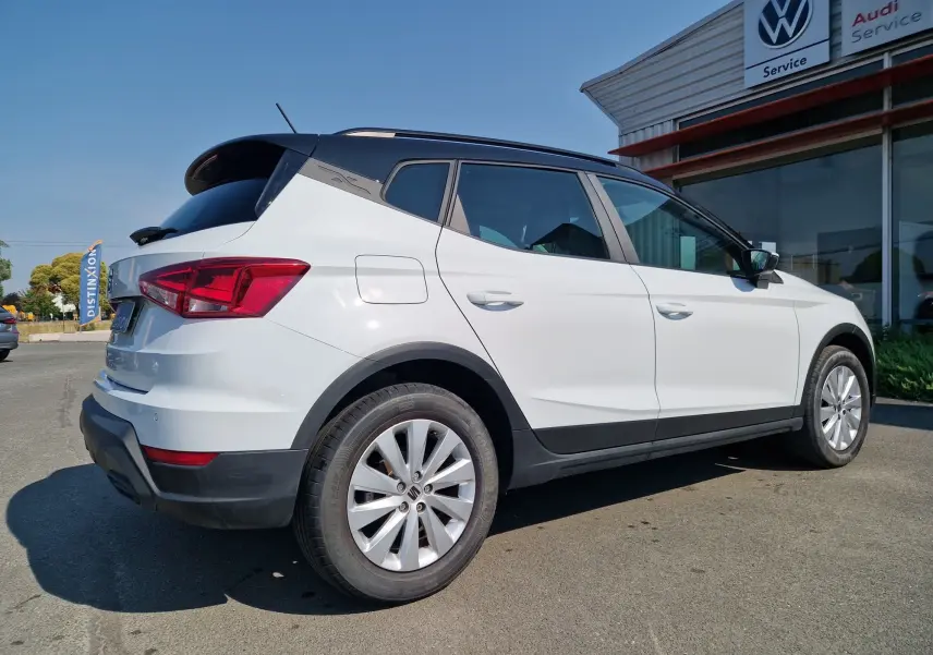 Vue 3/4 arrière droite du SEAT Arona blanc alpin avec toit noir, soulignant ses lignes modernes et ses jantes alliage.