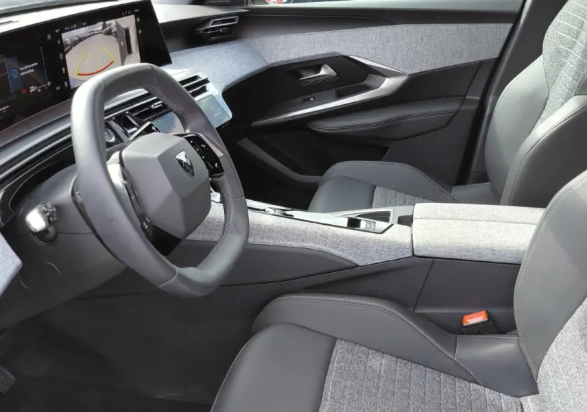 Vue intérieure côté conducteur du Peugeot 3008 Hybrid 136 e-DCS6 Allure 2025, avec cockpit numérique et sellerie grise tissu et cuir.