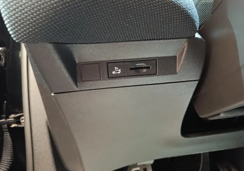 Détail intérieur montrant le bouton d'ouverture électrique du coffre sur la partie inférieure côté conducteur du Citroën C5 noir.