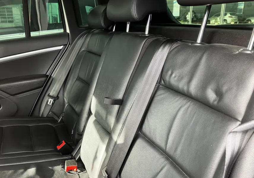 Vue rapprochée des sièges arrière en cuir noir du Volkswagen Tiguan 2013, avec ceintures de sécurité visibles.