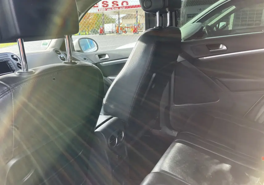 Vue intérieure côté droit du Volkswagen Tiguan 2013, sièges en cuir noir et console arrière avec aérateurs.