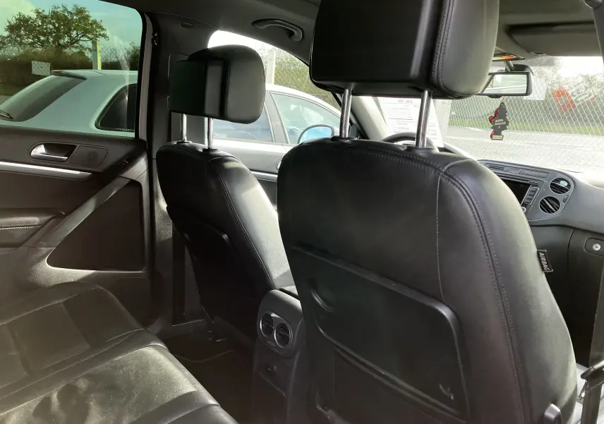 Vue intérieure arrière du Volkswagen Tiguan 2013, sièges en cuir noir et ventilation centrale entre les sièges avant.