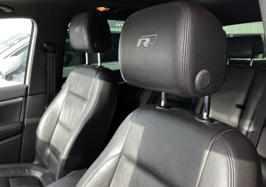 Gros plan sur les sièges avant en cuir noir du Volkswagen Tiguan Rline, avec logo "R" brodé sur les appuie-têtes.