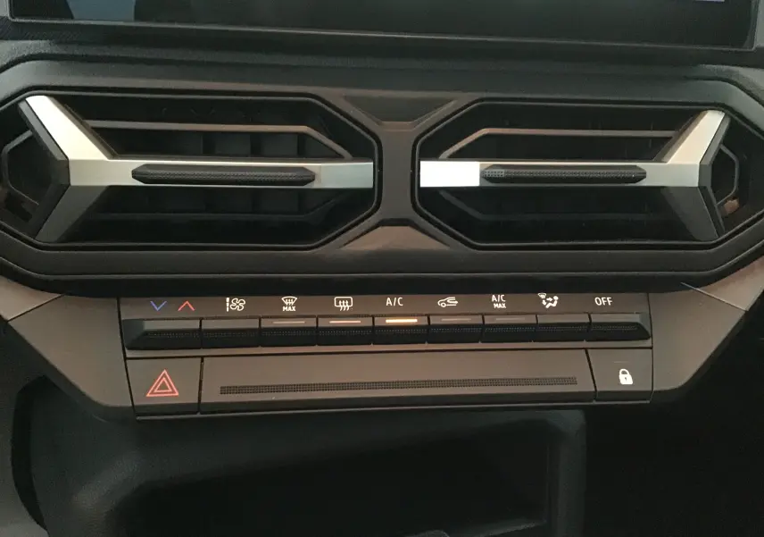Vue rapprochée des commandes de climatisation et des aérateurs du tableau de bord du Dacia Duster blanc glacier 2025.