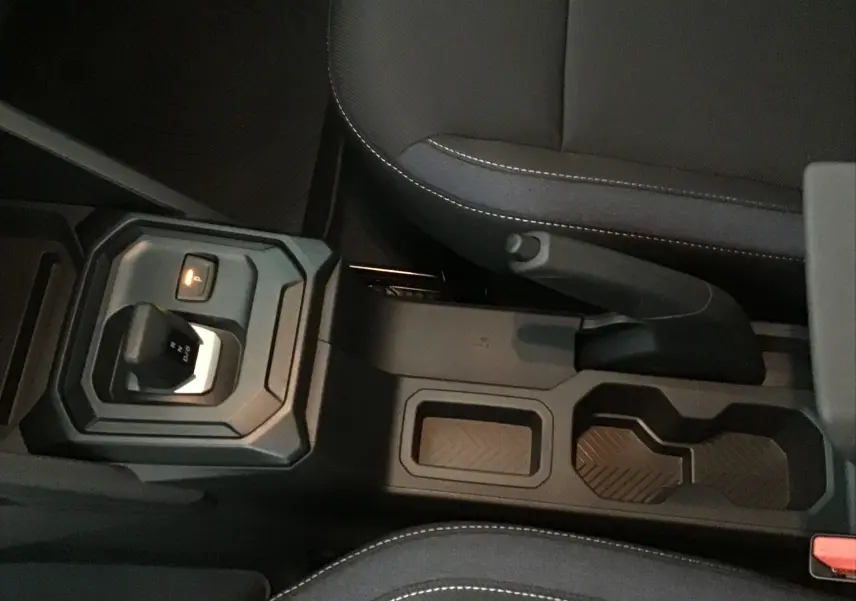 Vue rapprochée de la console centrale du Dacia Duster 2025 avec levier de boîte auto et frein à main manuel.