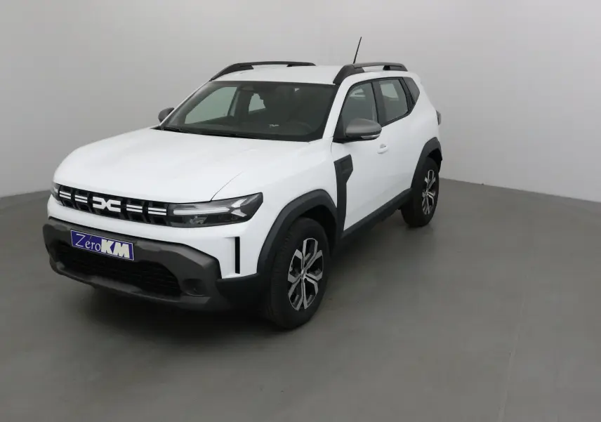 Vue 3/4 avant droite du Dacia Duster 2025 blanc glacier avec barres de toit noires et jantes alliage.