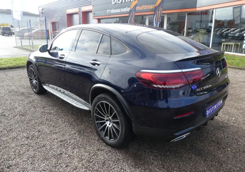 Mercedes GLC Coupé 300 de hybride bleu foncé vu en 3/4 arrière droit avec jantes AMG noires et marchepieds inox