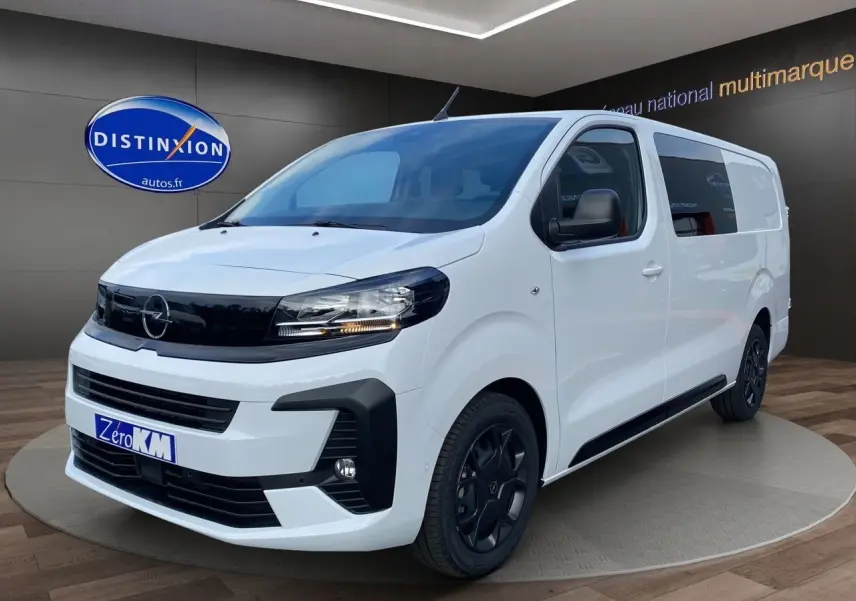 Opel Vivaro blanc en 3/4 avant droit avec jantes noires et calandre noire brillante dans un showroom.