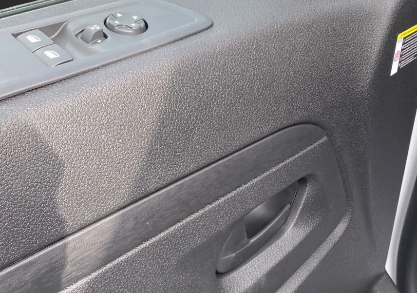 Gros plan sur la porte intérieure côté conducteur de l'Opel Vivaro blanc, avec commandes de vitres et poignée noire.