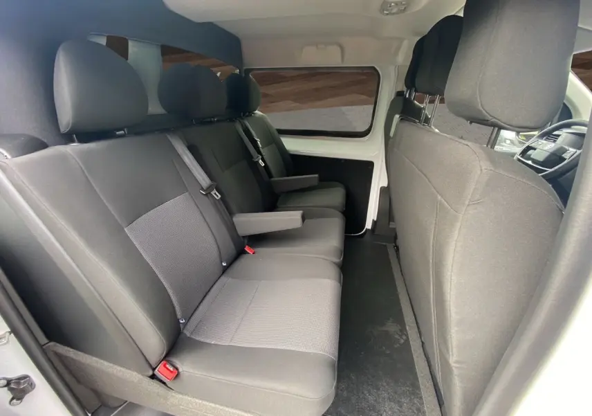 Vue intérieure côté gauche des sièges arrière noirs du fourgon blanc Opel Vivaro 2025 avec accoudoirs et ceintures visibles.