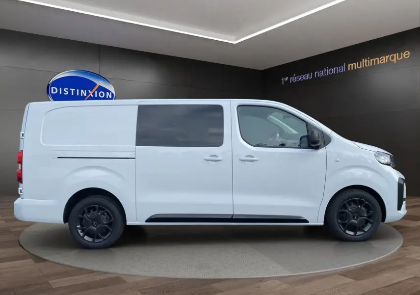 Profil droit d’un Opel Vivaro blanc 2025 avec vitres teintées et jantes noires en présentation showroom.
