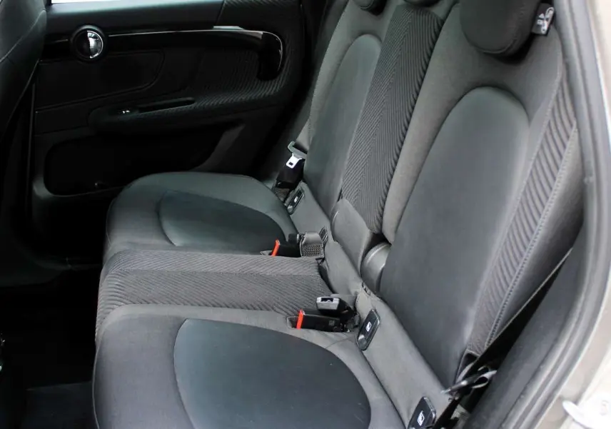 Vue intérieure côté droit des sièges arrière en tissu noir du MINI Countryman II Cooper SE 2018 avec porte ouverte.