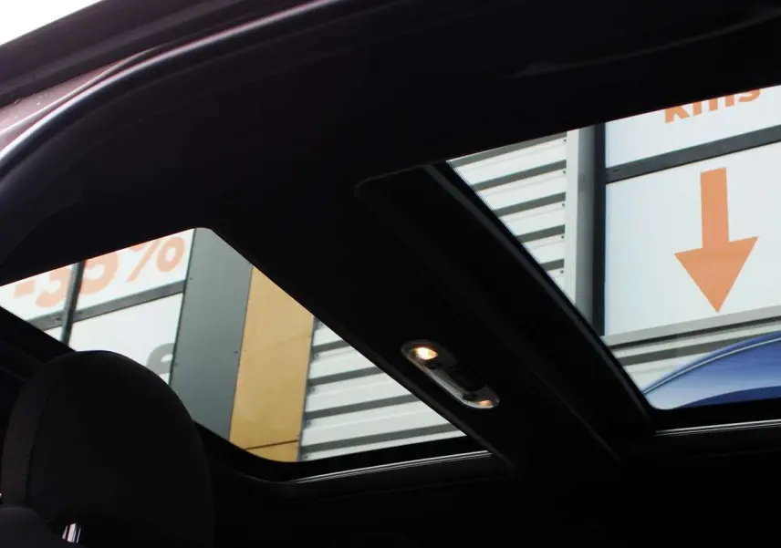 Toit panoramique ouvert montrant l'intérieur noir d'un MINI Countryman hybride Melting Silver avec toit noir.