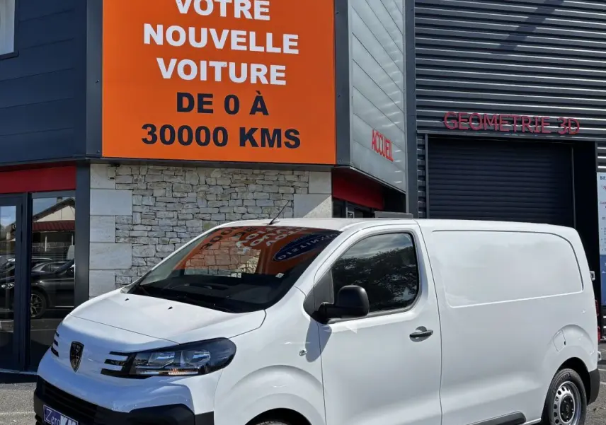 Peugeot Expert Fourgon blanc vu en 3/4 avant droit, stationné devant un bâtiment commercial avec panneau orange.