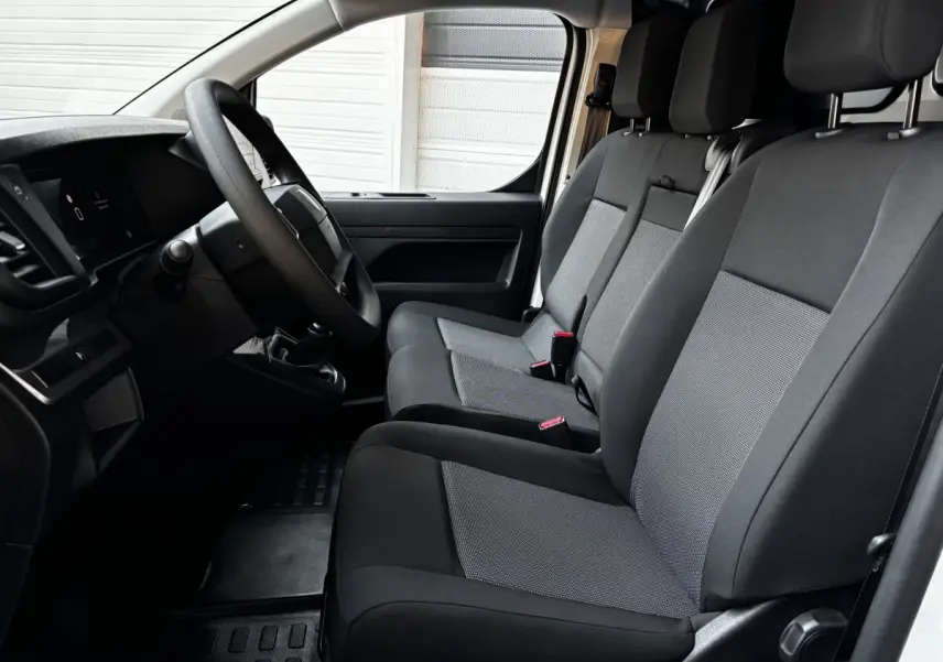 Vue intérieure côté conducteur du Peugeot Expert Fourgon 2025 avec sièges tissu gris et volant multifonctions.
