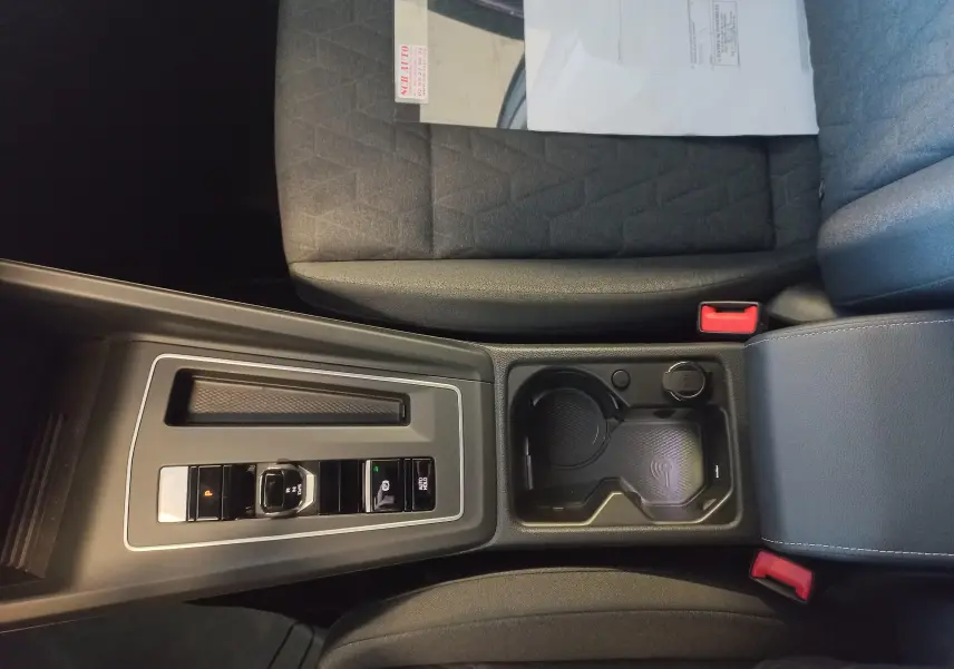 Vue intérieure centrée sur la console centrale de la Volkswagen Golf 1.5 eHybrid 2025 avec sièges tissu gris et commandes de boîte auto.