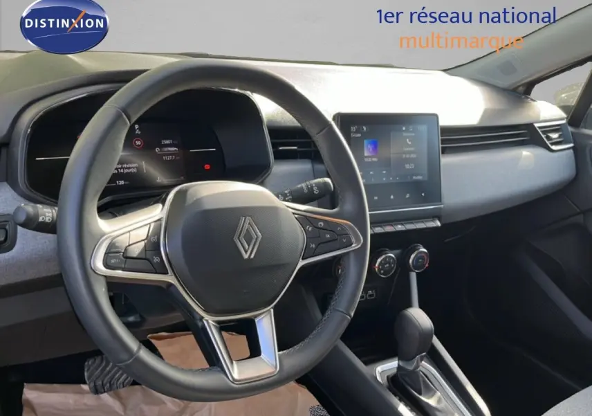 Vue intérieure centrée sur le volant et le tableau de bord de la Renault Clio gris schiste, avec écran tactile et commandes intégrées.