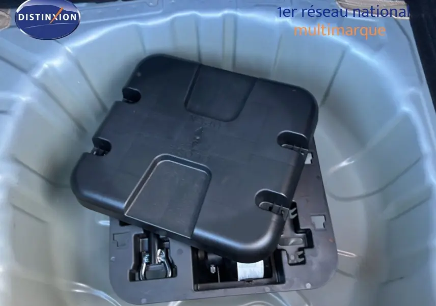 Coffre ouvert d’une Renault Clio gris schiste métal, montrant le rangement sous plancher avec kit de réparation pneus.