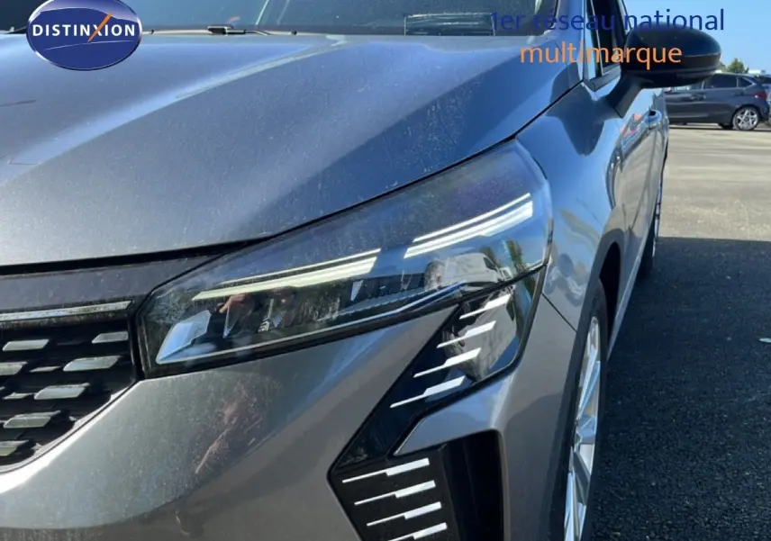 Gros plan sur l'avant droit de la Renault Clio gris schiste métal, mettant en valeur son phare LED et la calandre moderne.