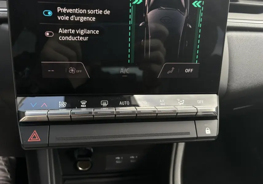 Vue rapprochée de la console centrale du Renault Captur gris Rafale, avec commandes climatisation et écran tactile affichant les aides à la conduite.