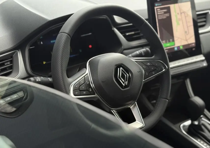 Vue rapprochée du volant noir perforé et du tableau de bord numérique du Renault Captur Gris Rafale 2025.