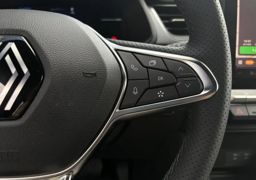 Gros plan sur le volant perforé côté droit du Renault Captur gris Rafale avec commandes multifonctions et tableau de bord numérique.