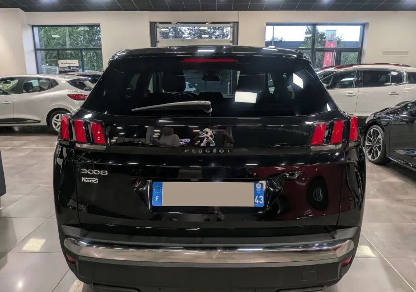 Vue arrière d'un Peugeot 3008 noir Perla 2022 dans un showroom, avec feux arrière distinctifs à trois griffes rouges.