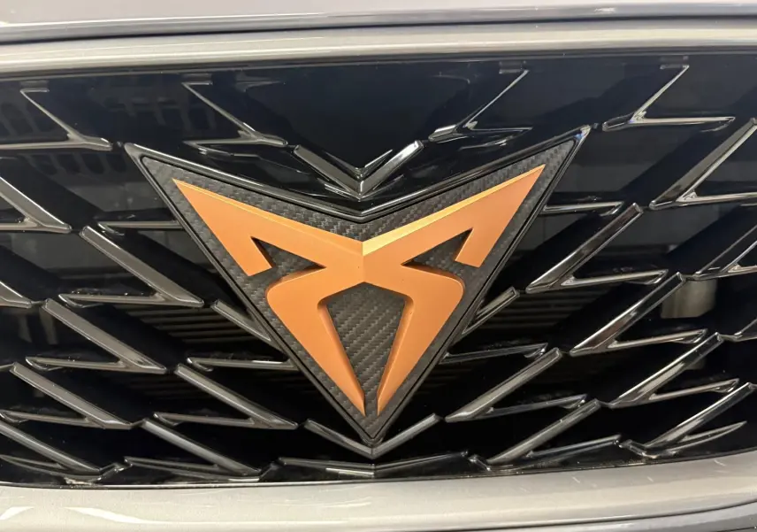 Gros plan sur la calandre noire avec le logo CUPRA cuivré, entourée de la carrosserie gris graphène.
