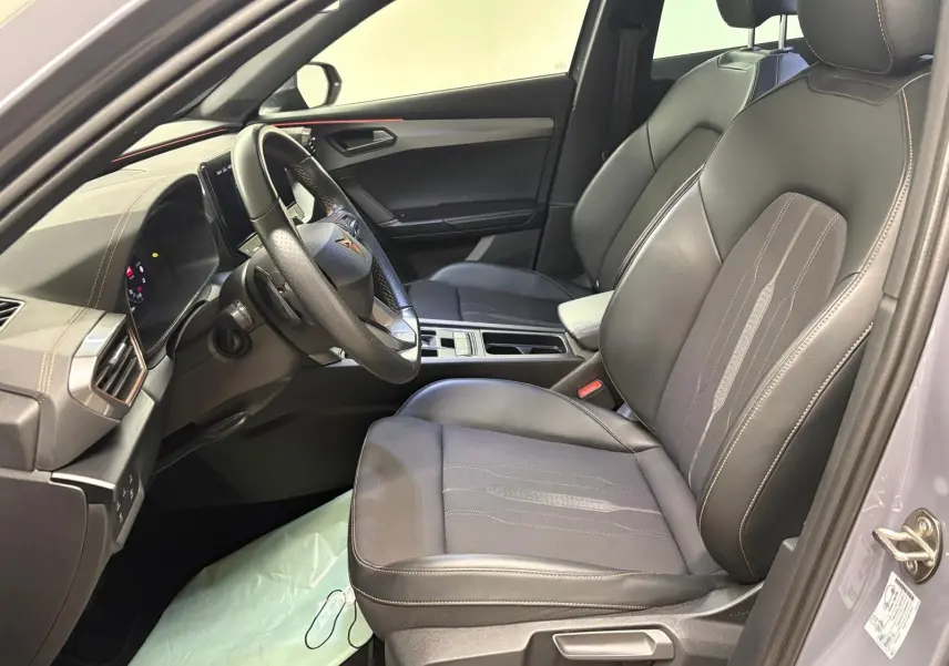 Vue intérieure côté conducteur de la CUPRA Formentor gris Graphène, sièges avant en cuir avec surpiqûres contrastées et volant multifonction.