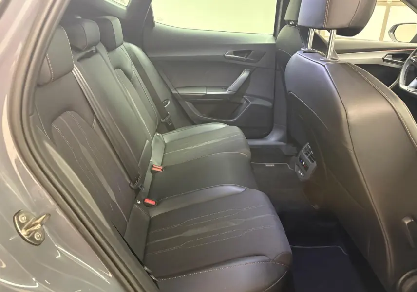 Vue intérieure côté arrière gauche du CUPRA Formentor gris Graphène, montrant les sièges arrière en cuir avec surpiqûres contrastées.