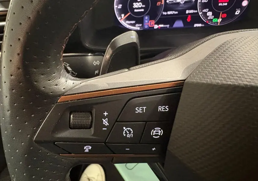 Gros plan sur les commandes au volant côté gauche du CUPRA Formentor gris Graphène, affichage numérique en arrière-plan.