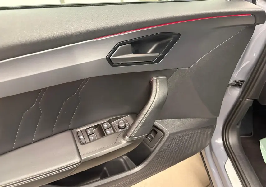 Vue rapprochée de la porte avant gauche d'une CUPRA Formentor gris graphène avec surpiqûres et commandes électriques.