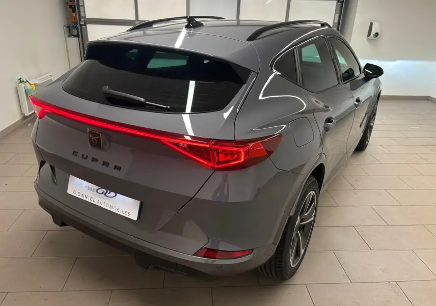 Vue 3/4 arrière droite du CUPRA Formentor gris Graphène avec feux arrière allumés et jantes 18 pouces en alliage.