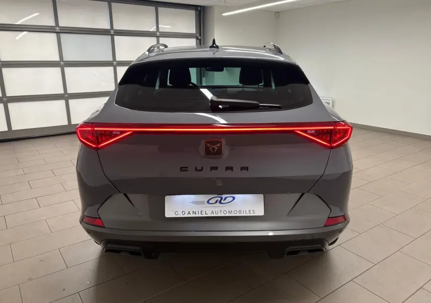 Vue arrière d'une CUPRA Formentor gris Graphène 2022 avec feux arrière allumés et hayon électrique en intérieur.