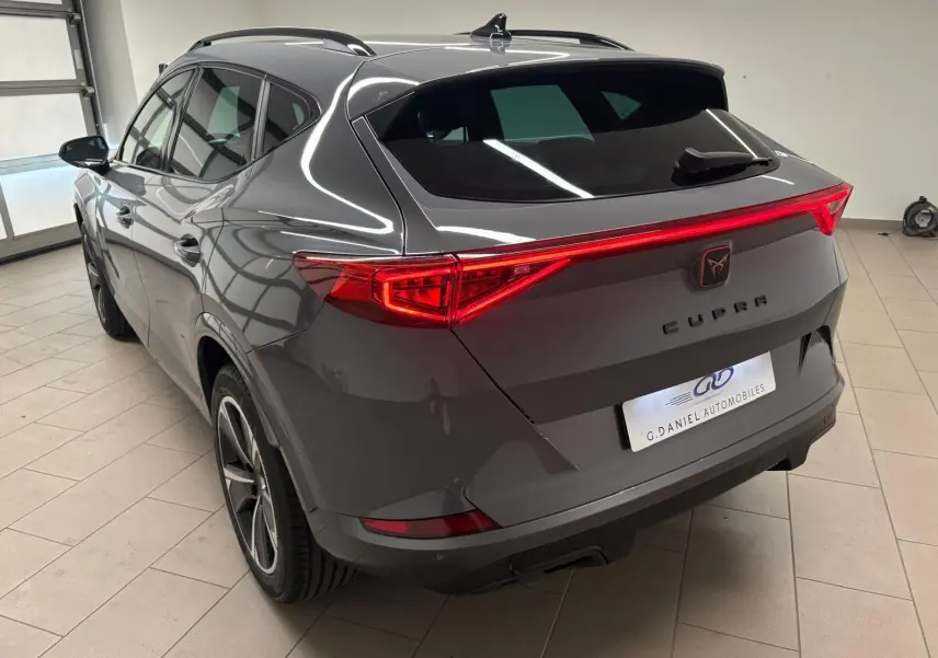 Vue 3/4 arrière droite du CUPRA Formentor gris Graphène avec feux arrière allumés et jantes 18 pouces en alliage.