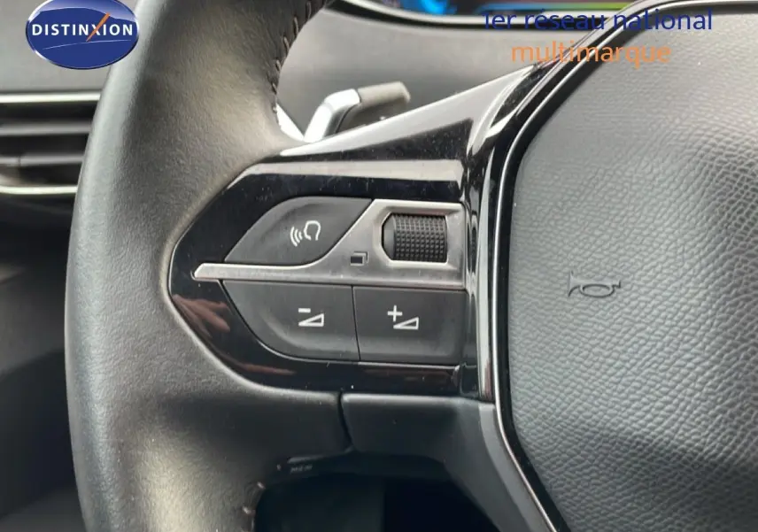 Gros plan sur les commandes gauche du volant noir du Peugeot 3008 hybride rechargeable 2024, avec boutons de volume et appel.