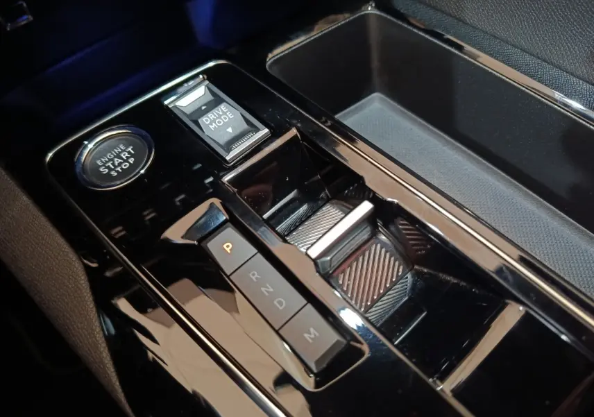 Gros plan sur la console centrale noire brillante du Peugeot 5008 avec bouton démarrage et sélecteur de mode de conduite.