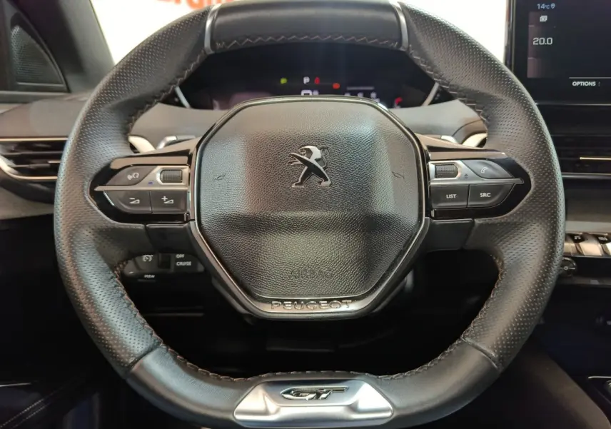Vue rapprochée du volant cuir noir du Peugeot 5008 GT 2023, avec commandes intégrées et logo central.