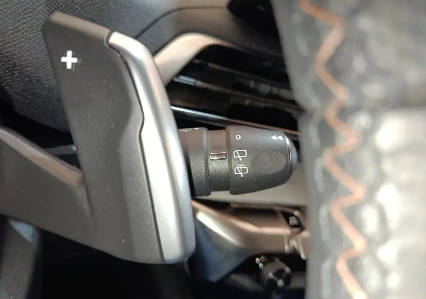 Gros plan sur la palette de changement de vitesse + côté gauche du volant cuir du Peugeot 5008 GT 2023, intérieur noir.