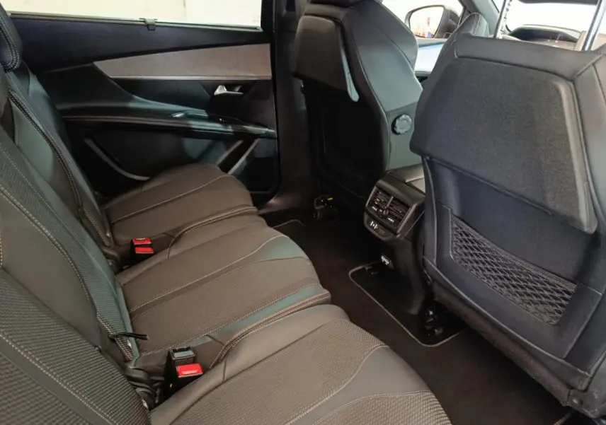 Vue intérieure côté gauche des sièges arrière noirs du Peugeot 5008 2023, avec aérations et rangements au dos des sièges avant.