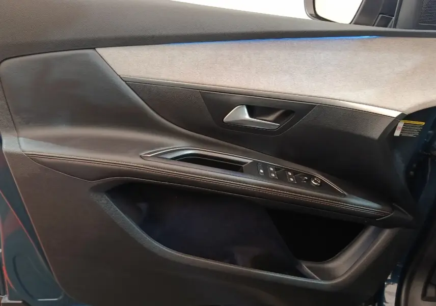 Vue rapprochée de la porte avant gauche du Peugeot 5008 bleu 2023, avec commandes de vitres et poignée argentée.