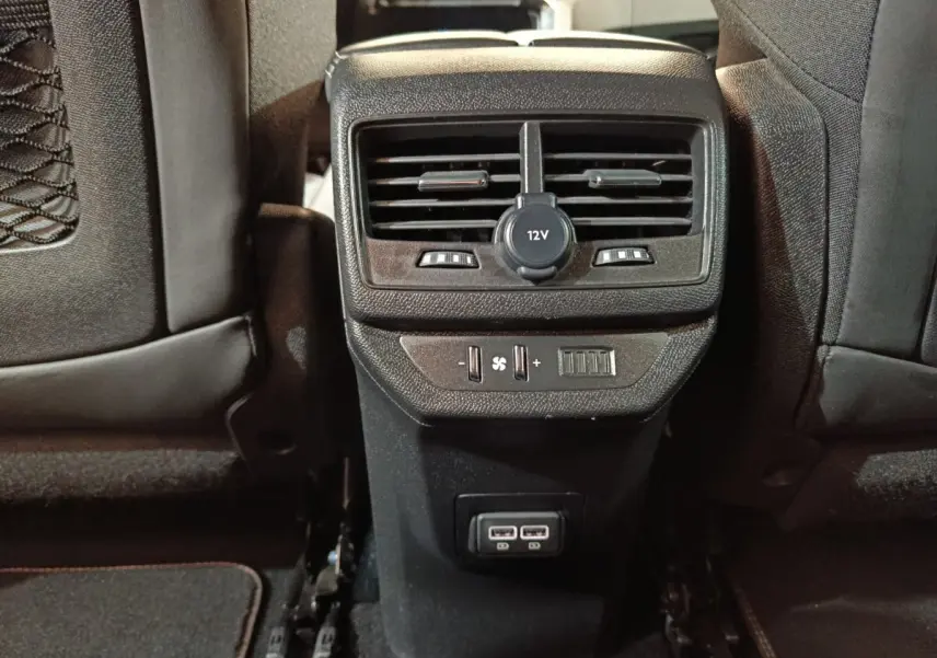 Vue rapprochée de la console arrière noire du Peugeot 5008 GT 2023 avec prises USB et commandes de ventilation.