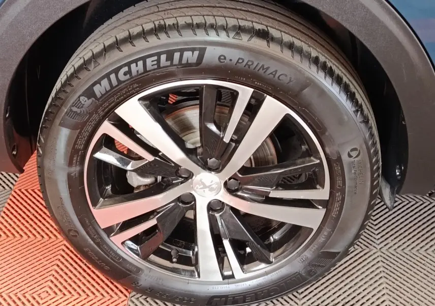 Gros plan sur la roue avant droite du Peugeot 5008 bleu, mettant en valeur la jante alliage bicolore et le pneu Michelin.