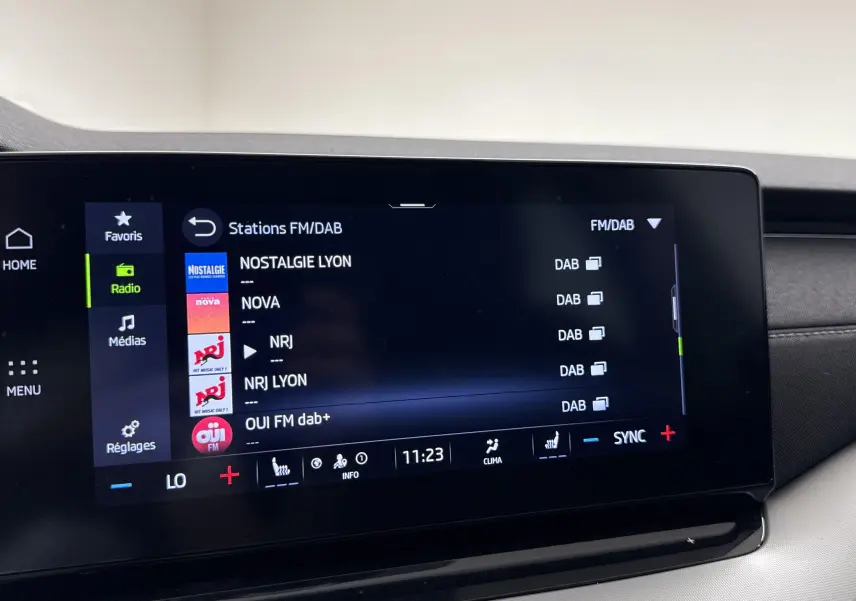 Écran tactile central de la Skoda Octavia Combi gris graphite 2023 affichant les stations radio FM/DAB en mode menu.