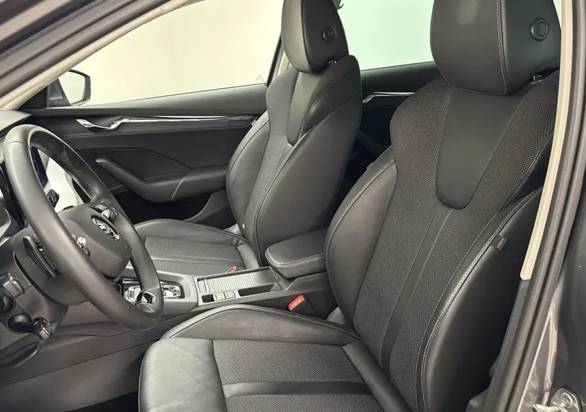 Intérieur avant droit de la Skoda Octavia Combi 2023 gris graphite, sièges en cuir noir avec coutures blanches visibles.